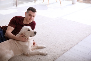 Photo of Handsome man with dog lying on carpet at home