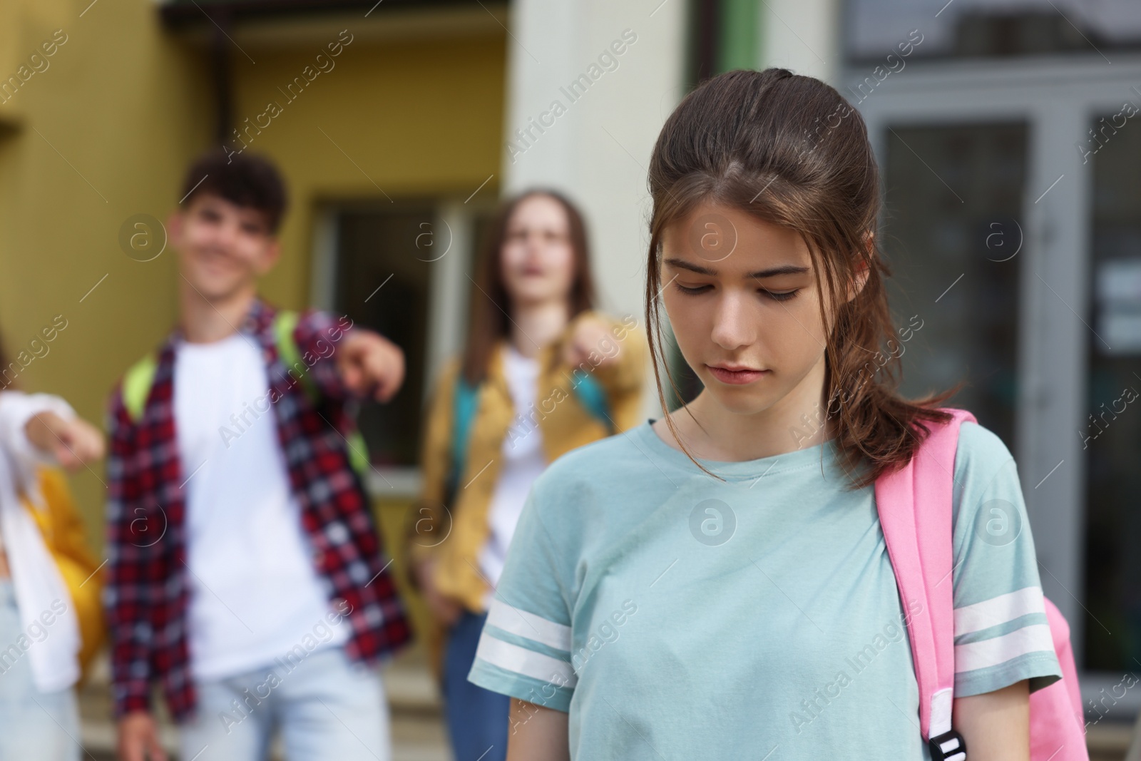 Photo of Teen problems. Students pointing at upset girl outdoors, selective focus