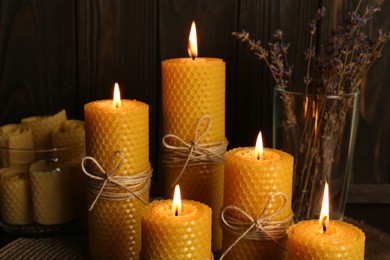 Beautiful burning beeswax candles and dried lavender flowers on table, closeup