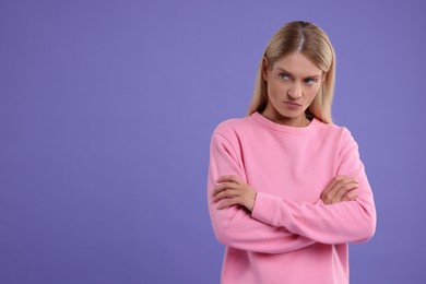 Photo of Resentful woman with crossed arms on purple background. Space for text