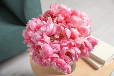 Photo of Beautiful bouquet of pink peonies in vase and books on wooden table indoors