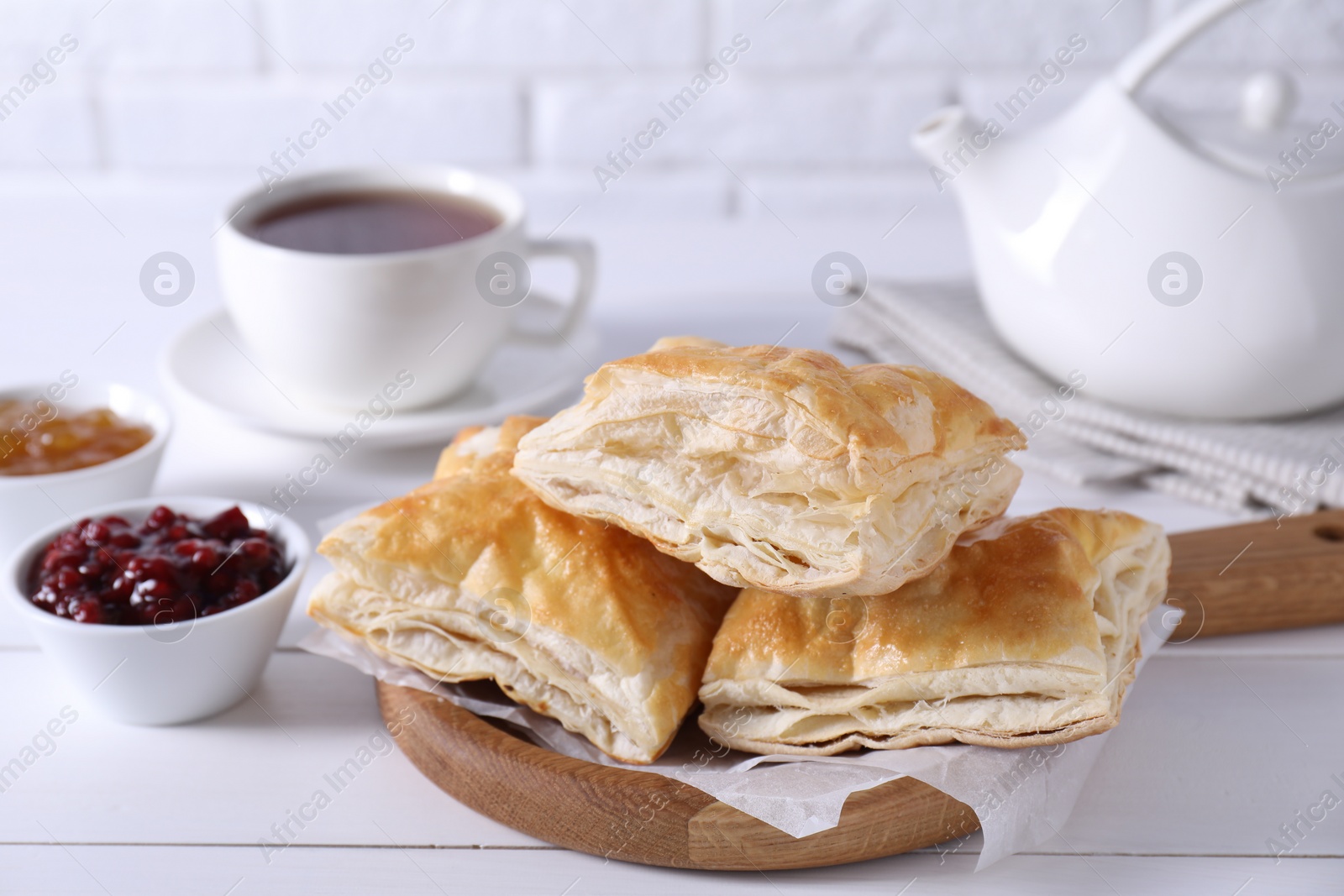 Photo of Delicious puff pastry served on white wooden table, closeup