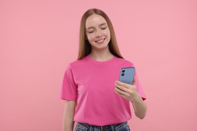Photo of Happy young woman using smartphone on pink background