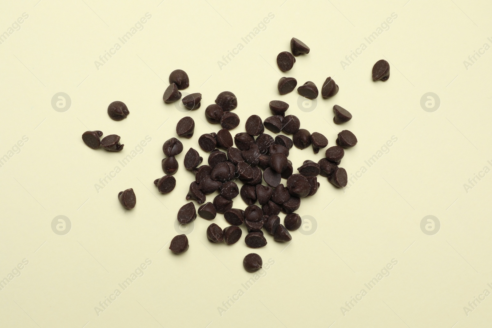 Photo of Pile of delicious chocolate chips on beige background, top view