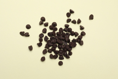 Photo of Pile of delicious chocolate chips on beige background, top view