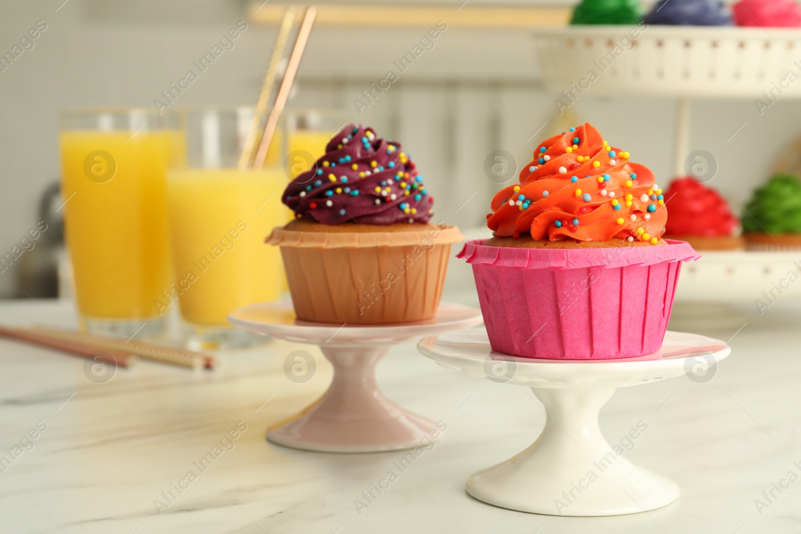 Photo of Delicious cupcakes with colorful cream and sprinkles on white table