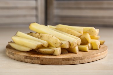 Photo of Cut raw potatoes on white wooden table, closeup