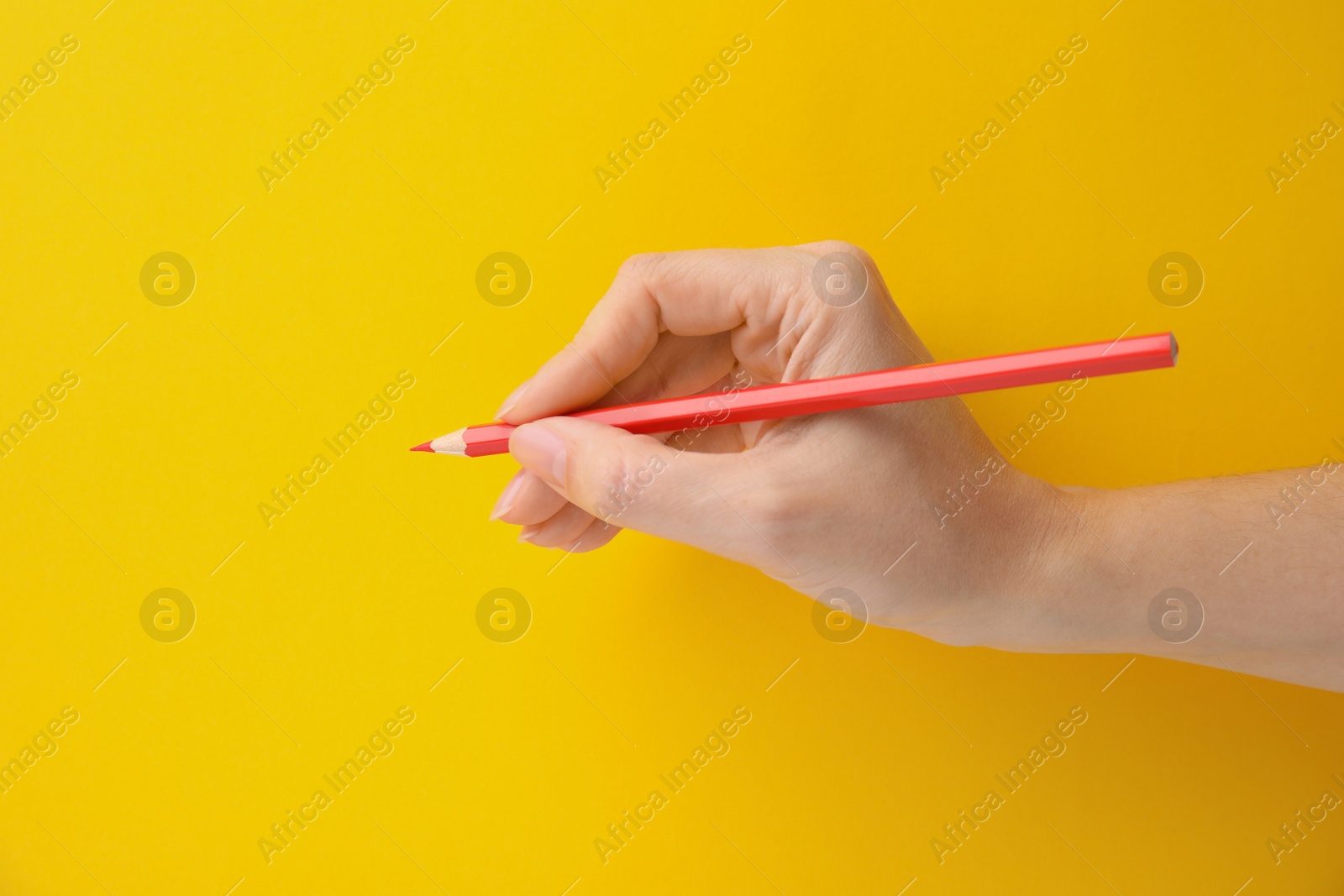 Photo of Woman with red pencil on yellow background, closeup