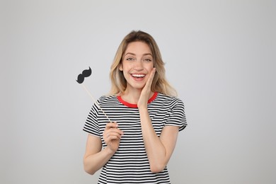 Funny woman with fake mustache on grey background