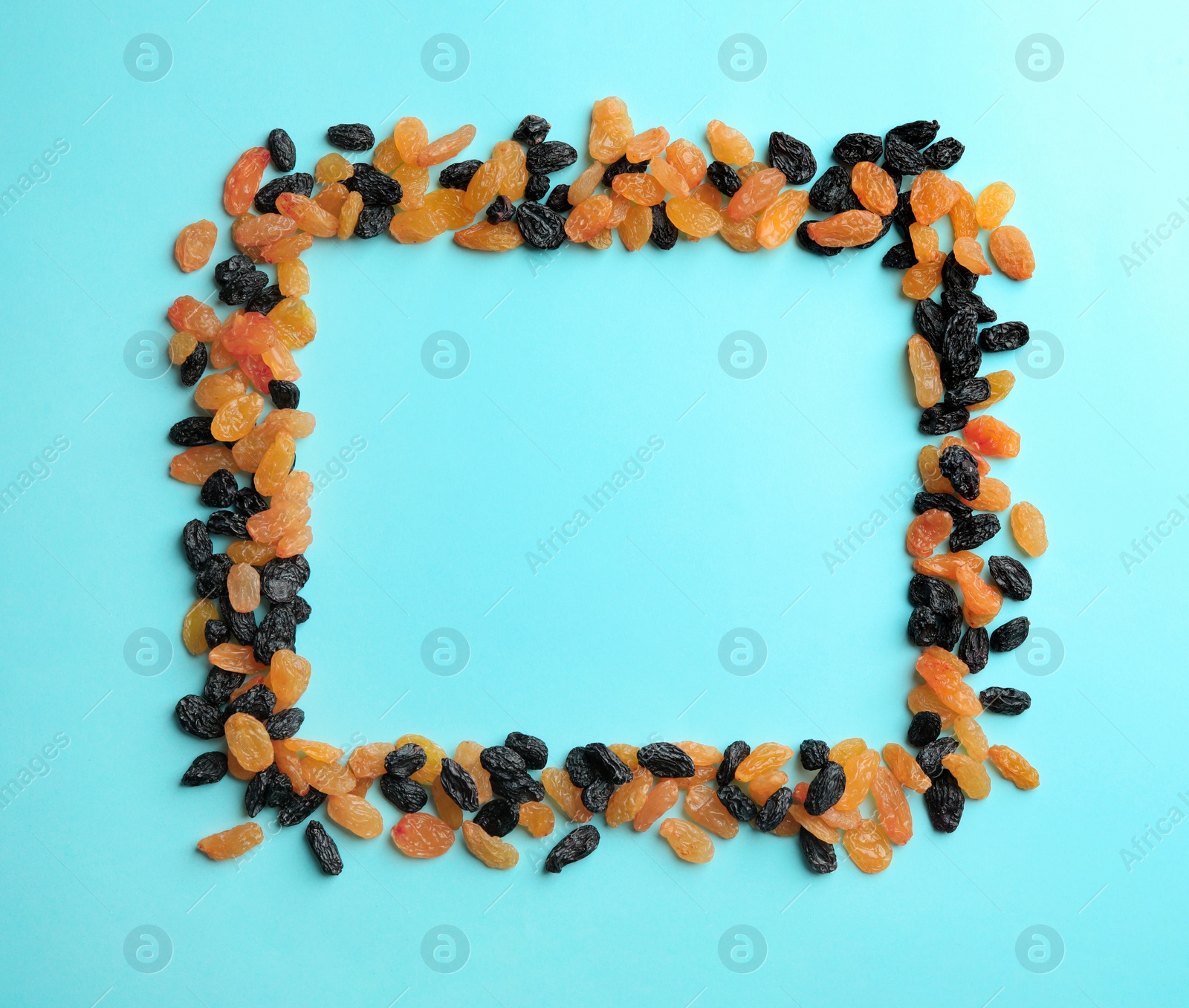 Photo of Frame made of raisins on color background, top view with space for text. Dried fruit as healthy snack