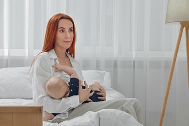 Mother breastfeeding her baby at home, space for text