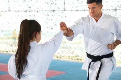 Girl practicing karate with coach on tatami outdoors