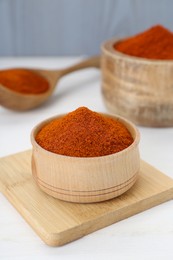 Bowls and spoon with aromatic paprika powder on white table