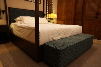 Photo of Large bed with soft bench in comfortable hotel room