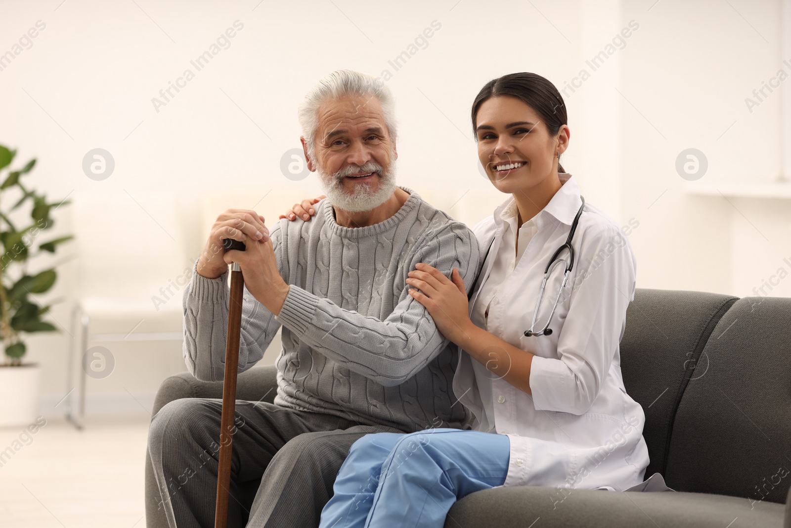 Photo of Smiling nurse supporting elderly patient in hospital