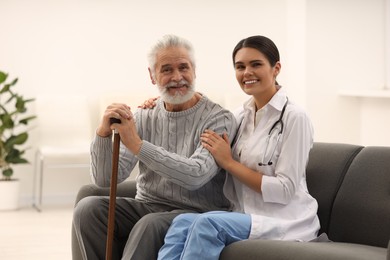 Smiling nurse supporting elderly patient in hospital