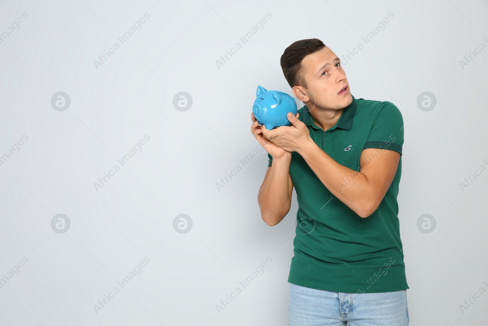 Photo of Young man with piggy bank on white background. Space for text