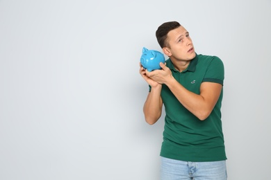 Young man with piggy bank on white background. Space for text