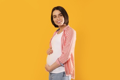 Happy young pregnant woman on yellow background