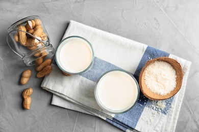 Glasses with coconut and peanut milk on grey background, top view