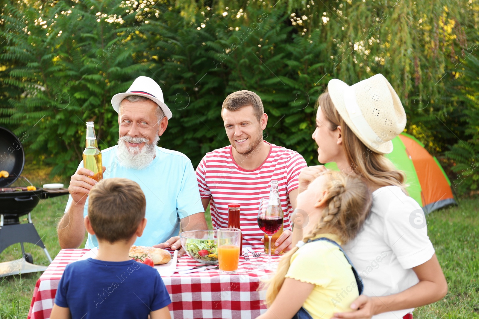 Photo of Happy family having barbecue in park on sunny day