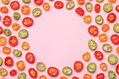 Photo of Frame made with different cut chili peppers on pink background, flat lay. Space for text