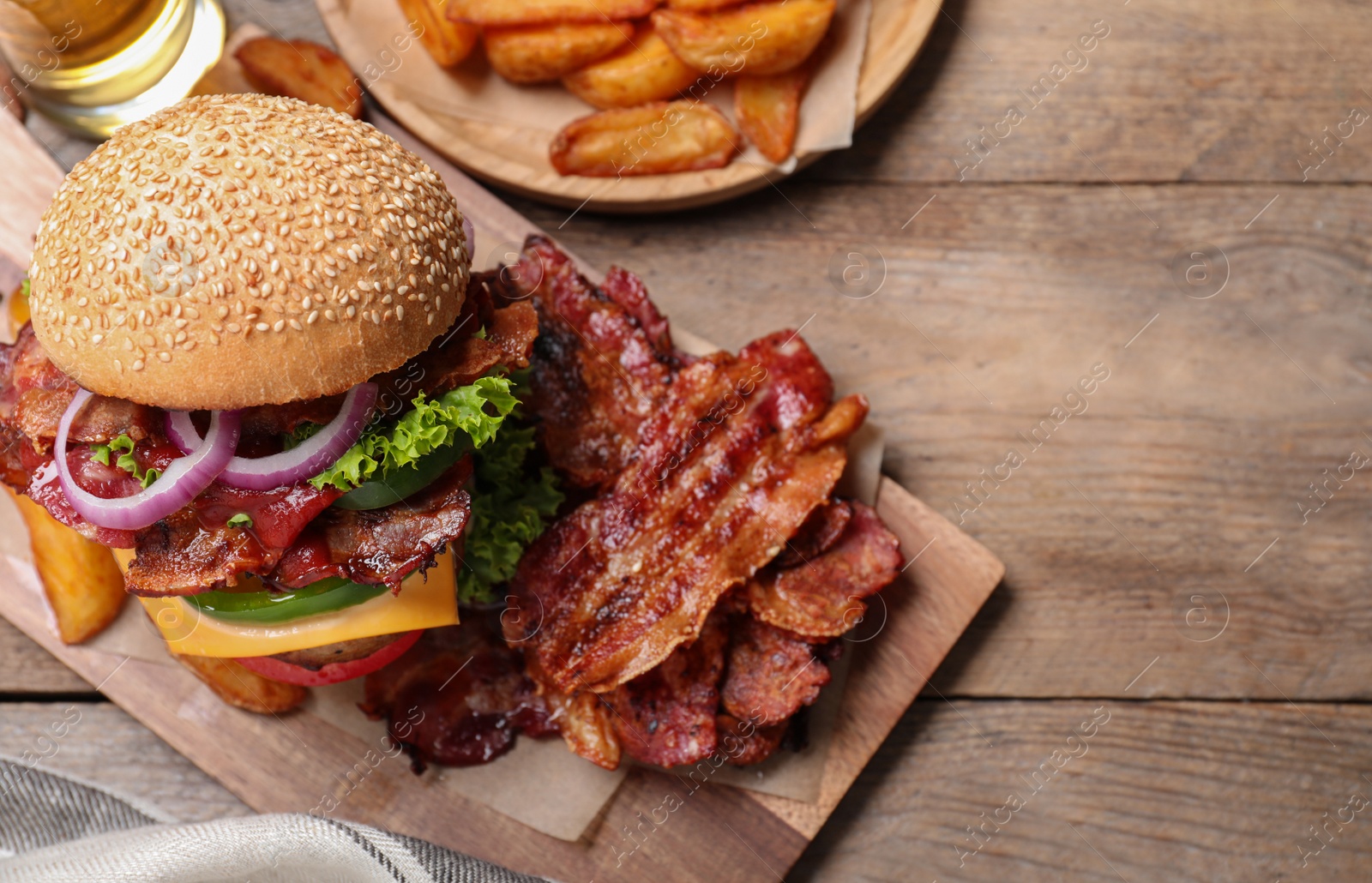 Photo of Composition with juicy bacon burger on wooden table, above view. Space for text