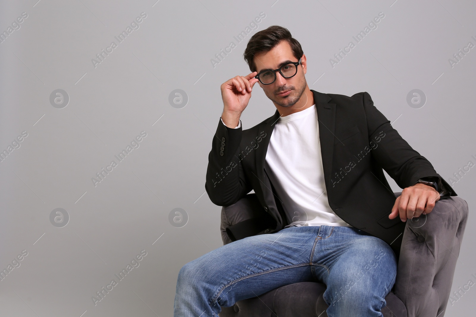 Photo of Handsome young businessman sitting in armchair on grey background. Space for text