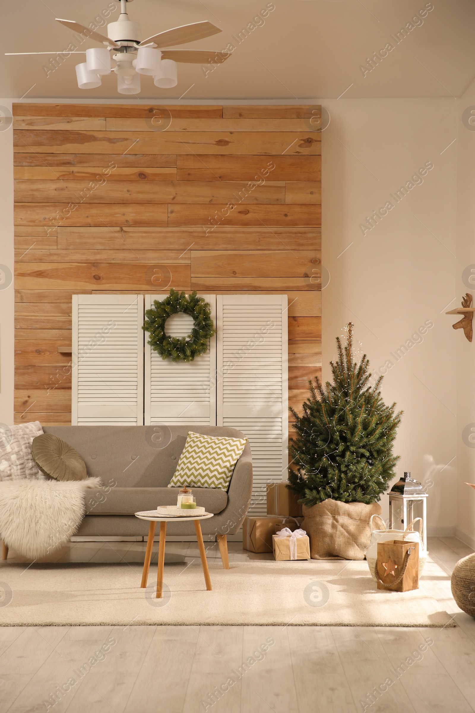 Photo of Spacious room with small Christmas tree and wreath. Interior design