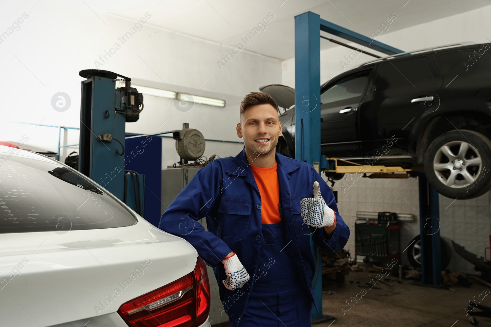 Photo of Portrait of professional mechanic near lifted car at automobile repair shop