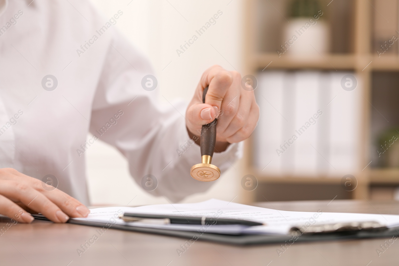 Photo of Woman stamping document at table, closeup view
