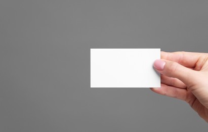 Photo of Woman holding blank business card on grey background, closeup. Space for text