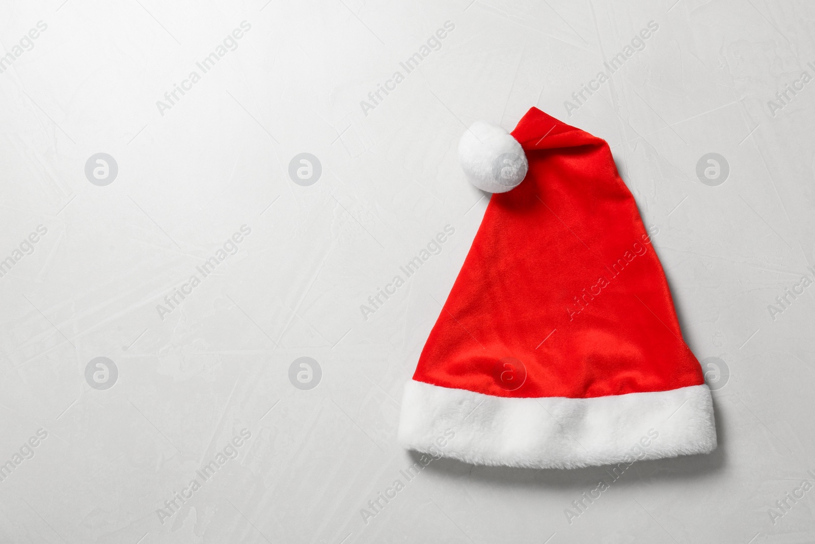 Photo of Santa Claus hat on light grey background, top view. Space for text