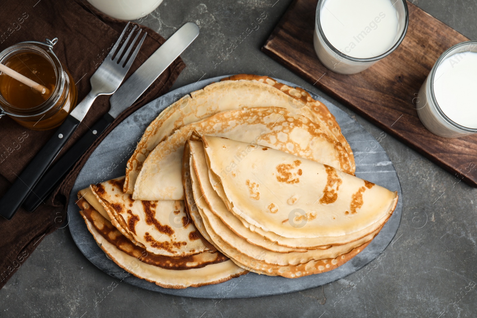 Photo of Flat lay composition with fresh thin pancakes on grey table