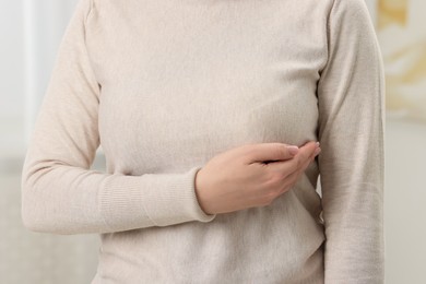 Mammology. Young woman doing breast self-examination at home, closeup