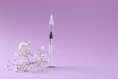 Photo of Cosmetology. Medical syringe and gypsophila on violet background, space for text