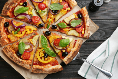 Photo of Tasty vegetable pizza on black wooden table, flat lay