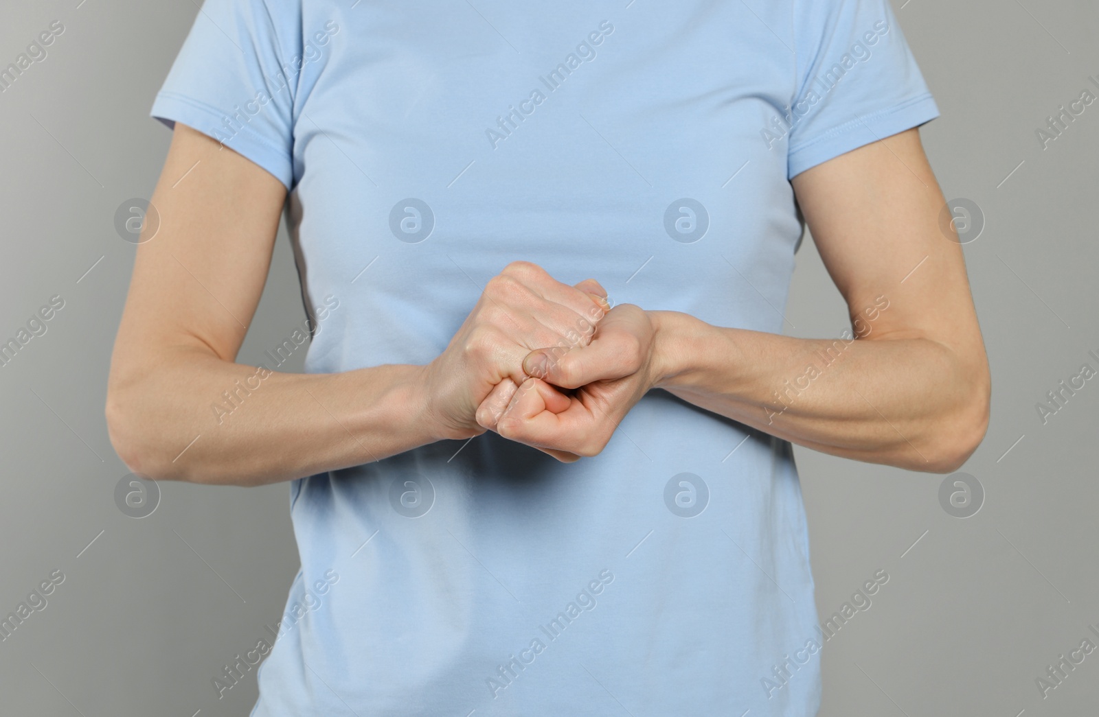 Photo of Woman cracking her knuckles on light grey background, closeup. Bad habit