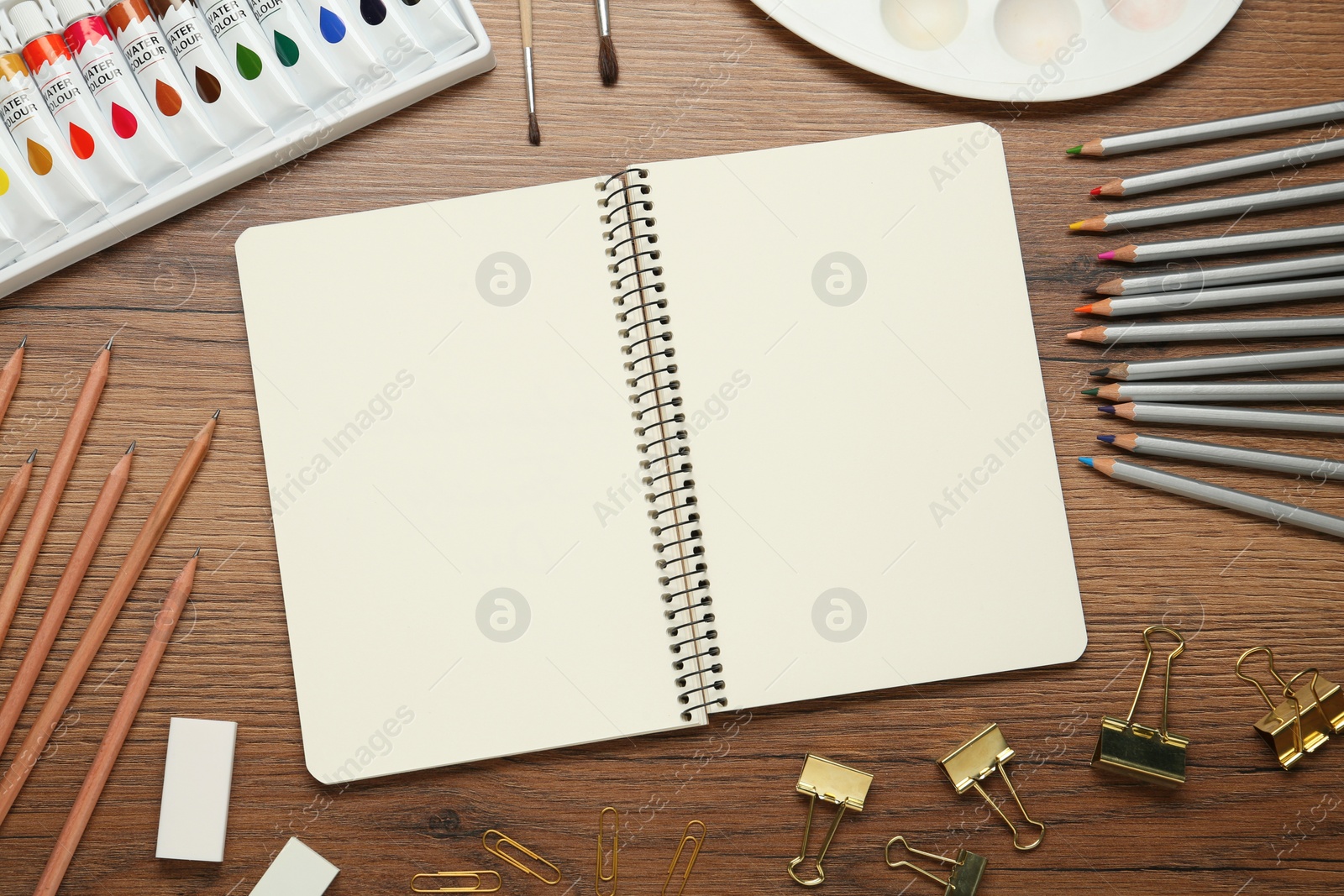 Photo of Flat lay composition with sketchbook and drawing tools on wooden table