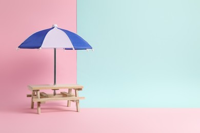 Photo of Small wooden holder with toy umbrella on color background, space for text