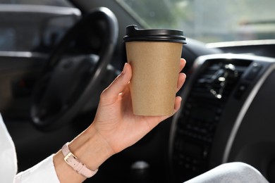 Photo of Coffee to go. Woman with paper cup of drink in car, closeup