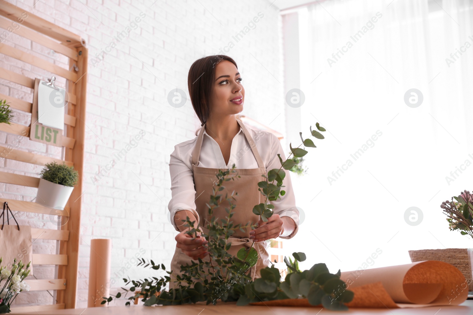 Photo of Florist making beautiful bouquet at table in workshop