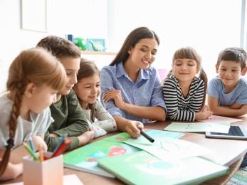 Cute little children with teacher in classroom at school