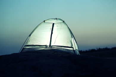 Photo of Small camping tent glowing in twilight outdoors