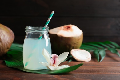 Photo of Glass jar of coconut water and beautiful flower on wooden table