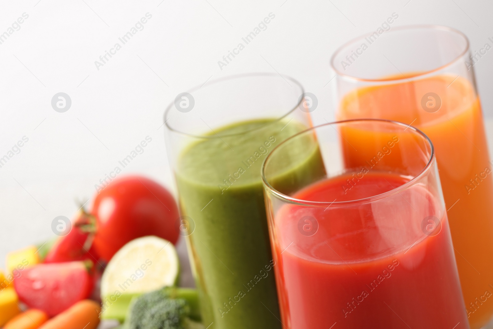 Photo of Different tasty juices in glasses on white background, closeup. Space for text