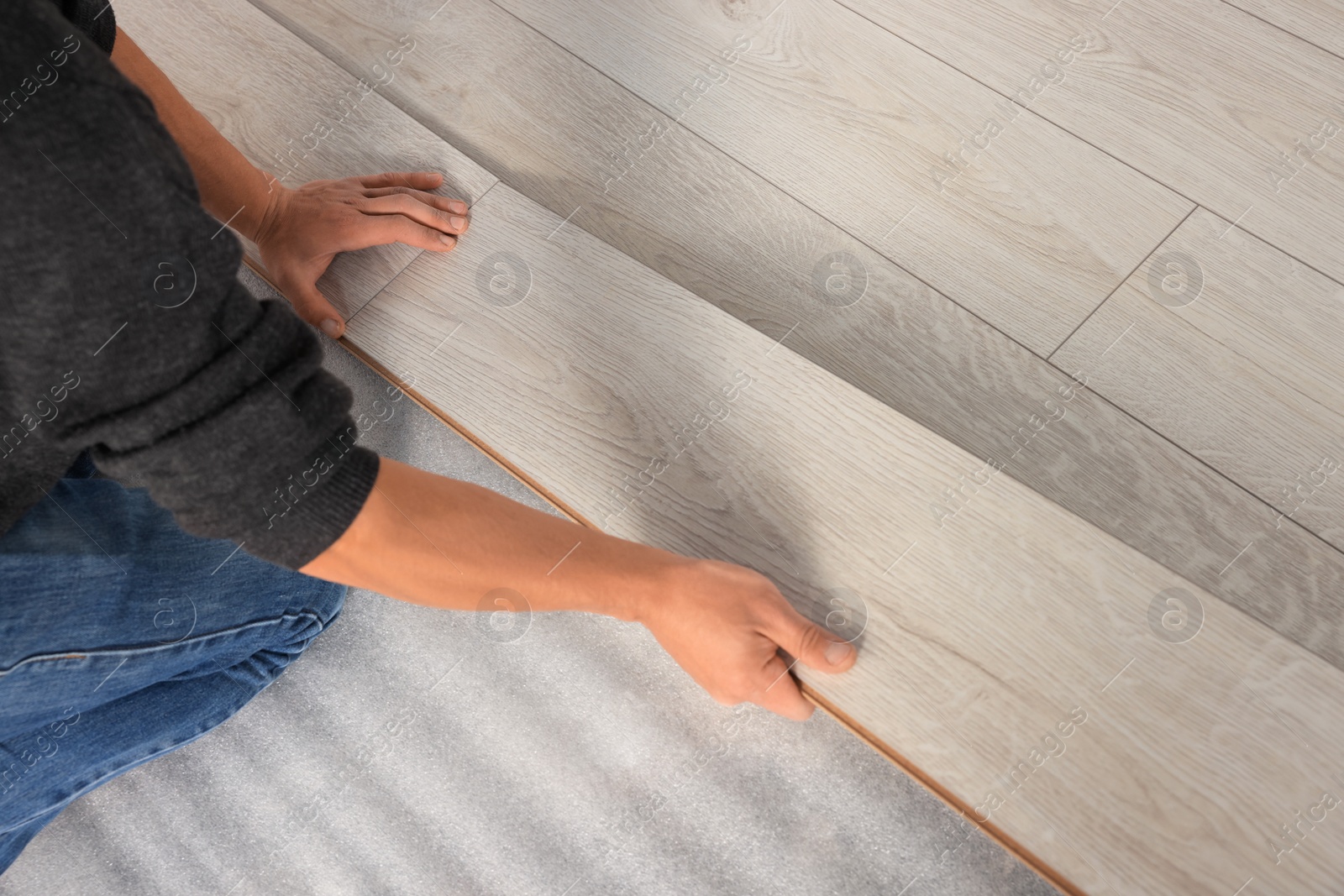 Photo of Professional worker installing new laminate flooring, closeup. Space for text