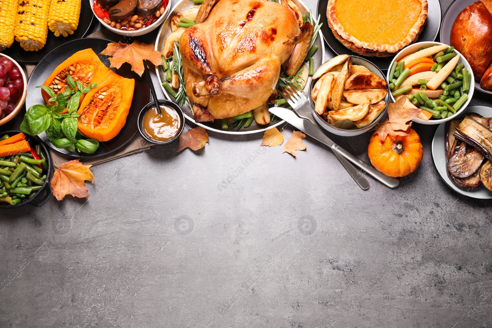 Photo of Traditional Thanksgiving day feast with delicious cooked turkey and other seasonal dishes served on grey table, flat lay. Space for text