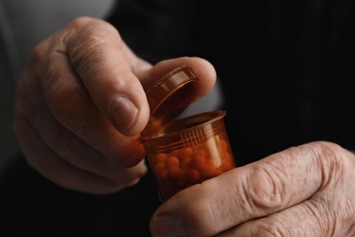 Photo of Senior man holding bottle with pills, closeup of hands