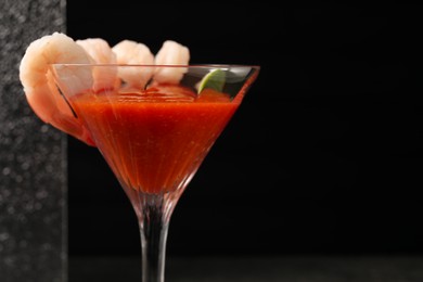 Tasty shrimp cocktail with sauce in glass on dark background, closeup. Space for text